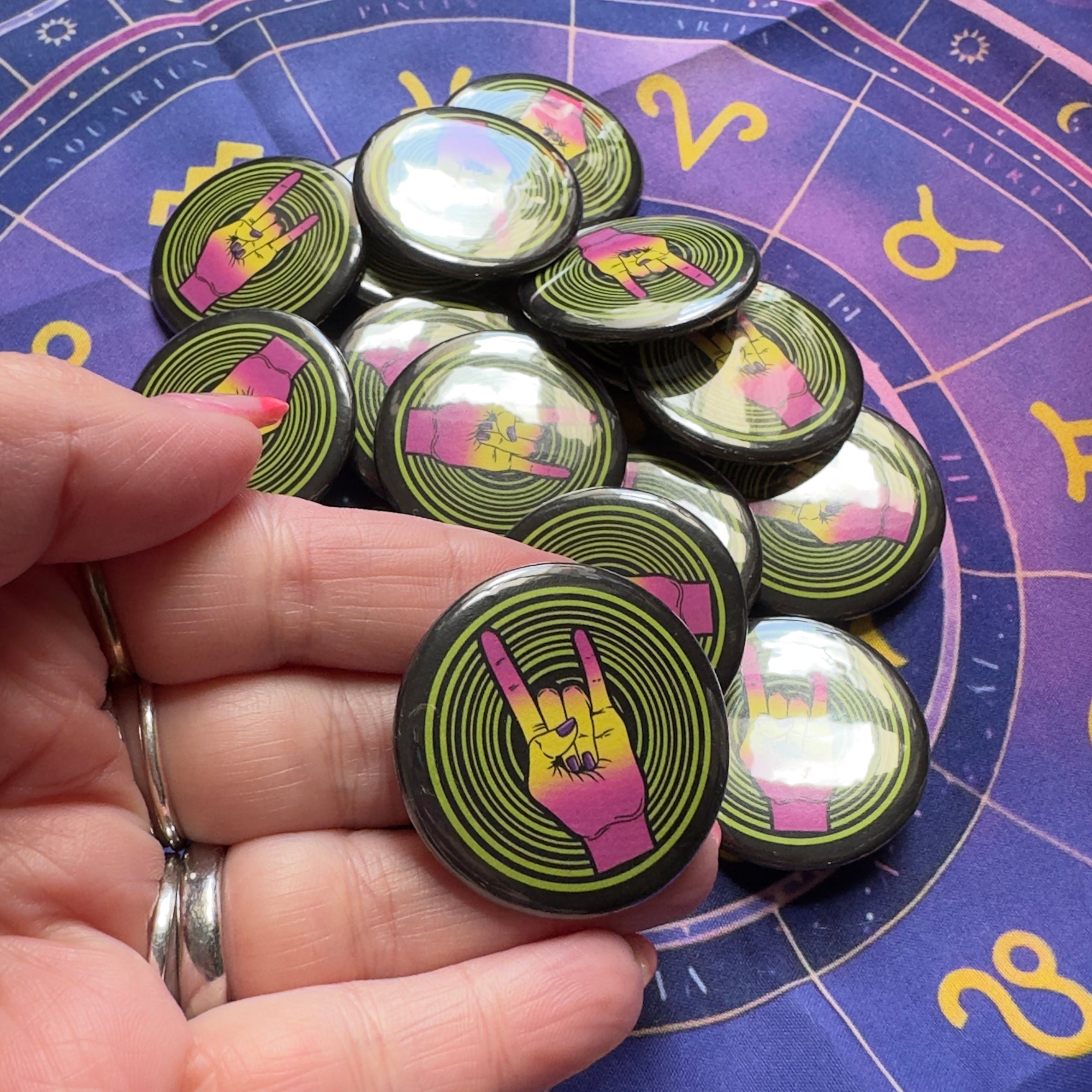Buttons with a heavy metal horns hand sign held over an astrological chart
